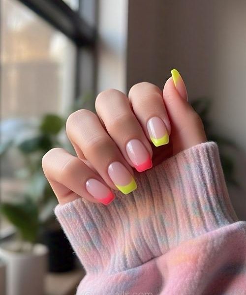 9. Neon-tipped nails, hands tucked into cozy long sleeves.